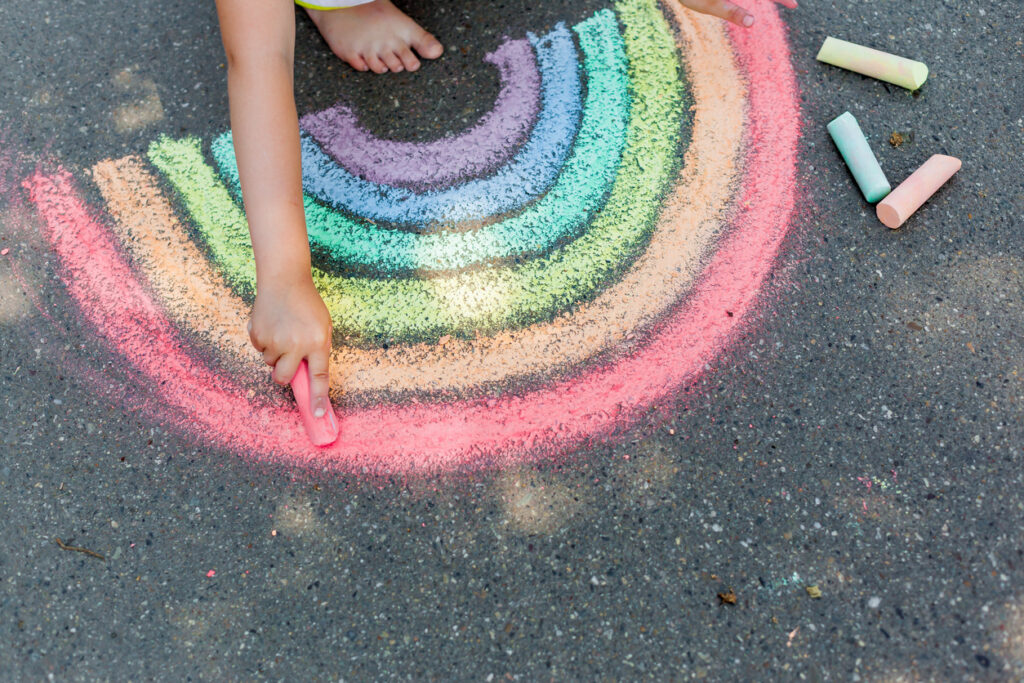 Mindfulness for Kids: A Powerful Tool for Self-Regulation the child girl draws a rainbow with colored chalk on the asphalt. child drawings paintings concept. education and arts, be creative when back to school