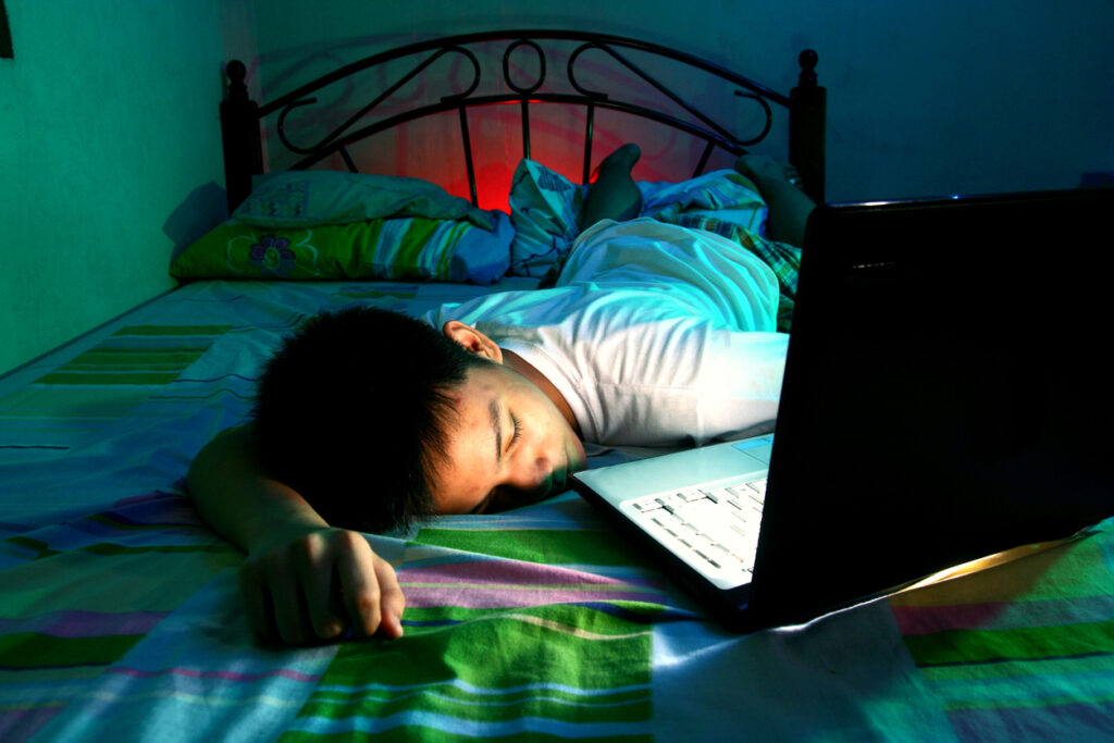 📱 Screen Time & Kids: Finding a Healthy Balance teenager sleeping in front of a computer on a bed