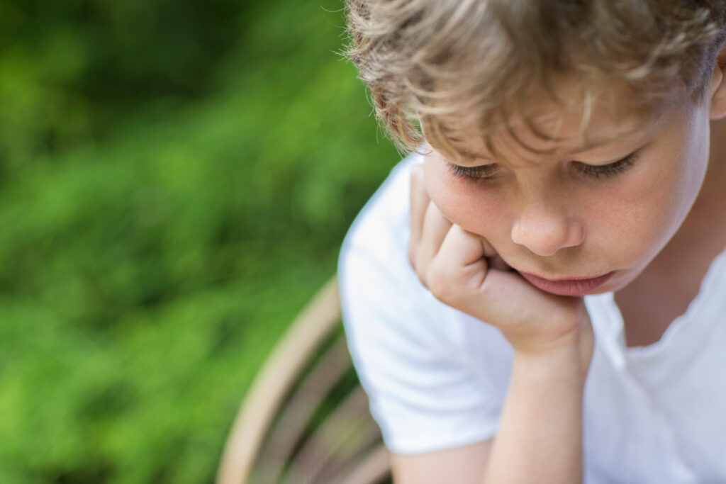 Separation Anxiety: When It’s More Than Just Growing Pains close up of unhappy boy sitting in chair outdoors