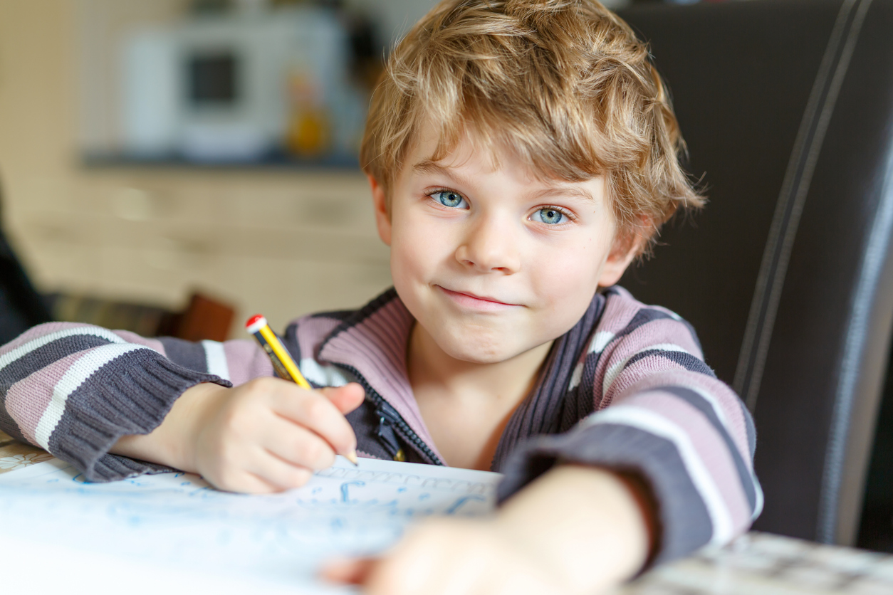 happy school kid boy at home making homework